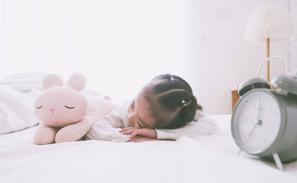 children sleep on bed with alarm clock early morning